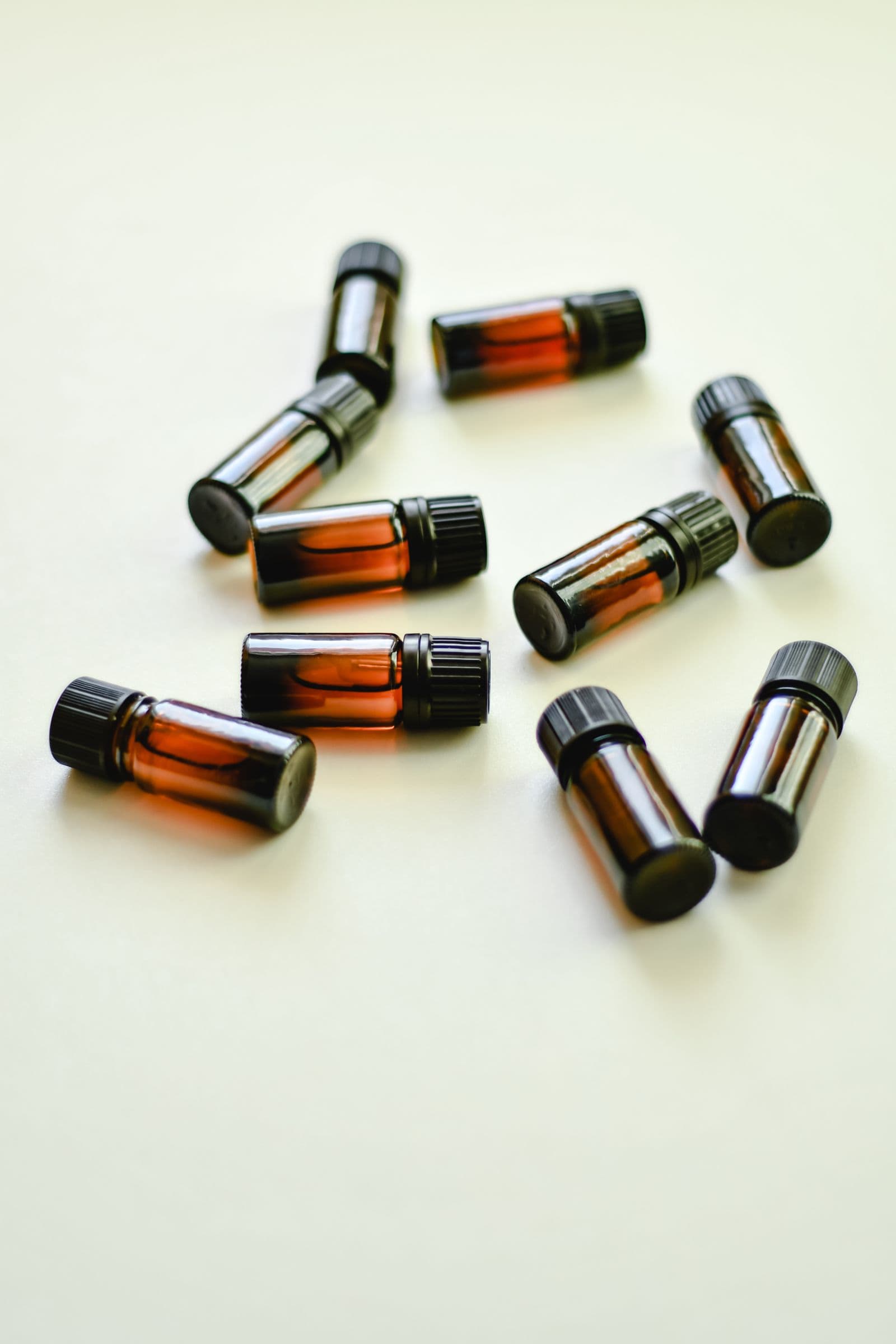 Small amber roller and dropper bottles scattered loosely across a pale surface.