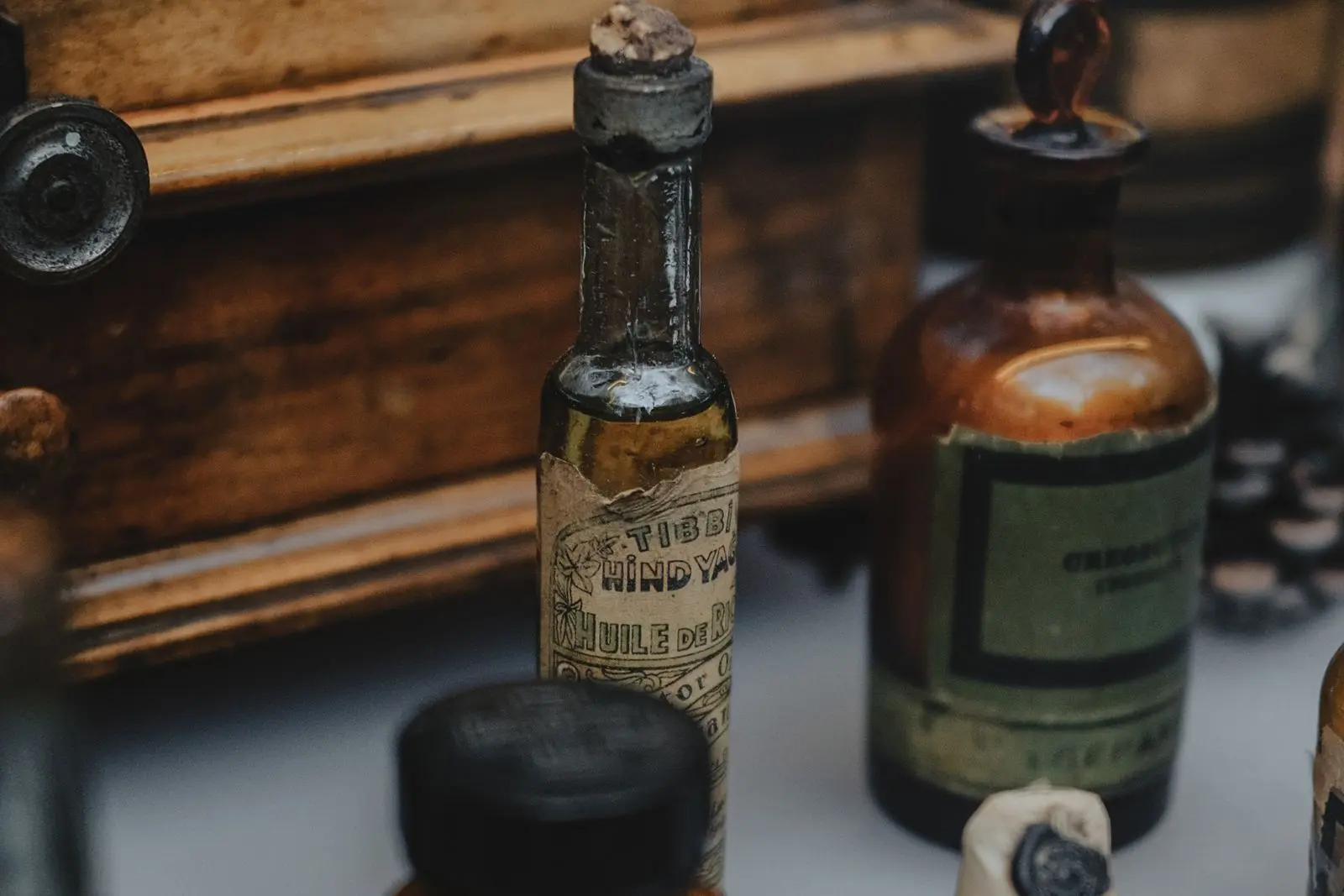 Vintage apothecary bottles and small glass vials arranged in a wooden medicine cabinet.