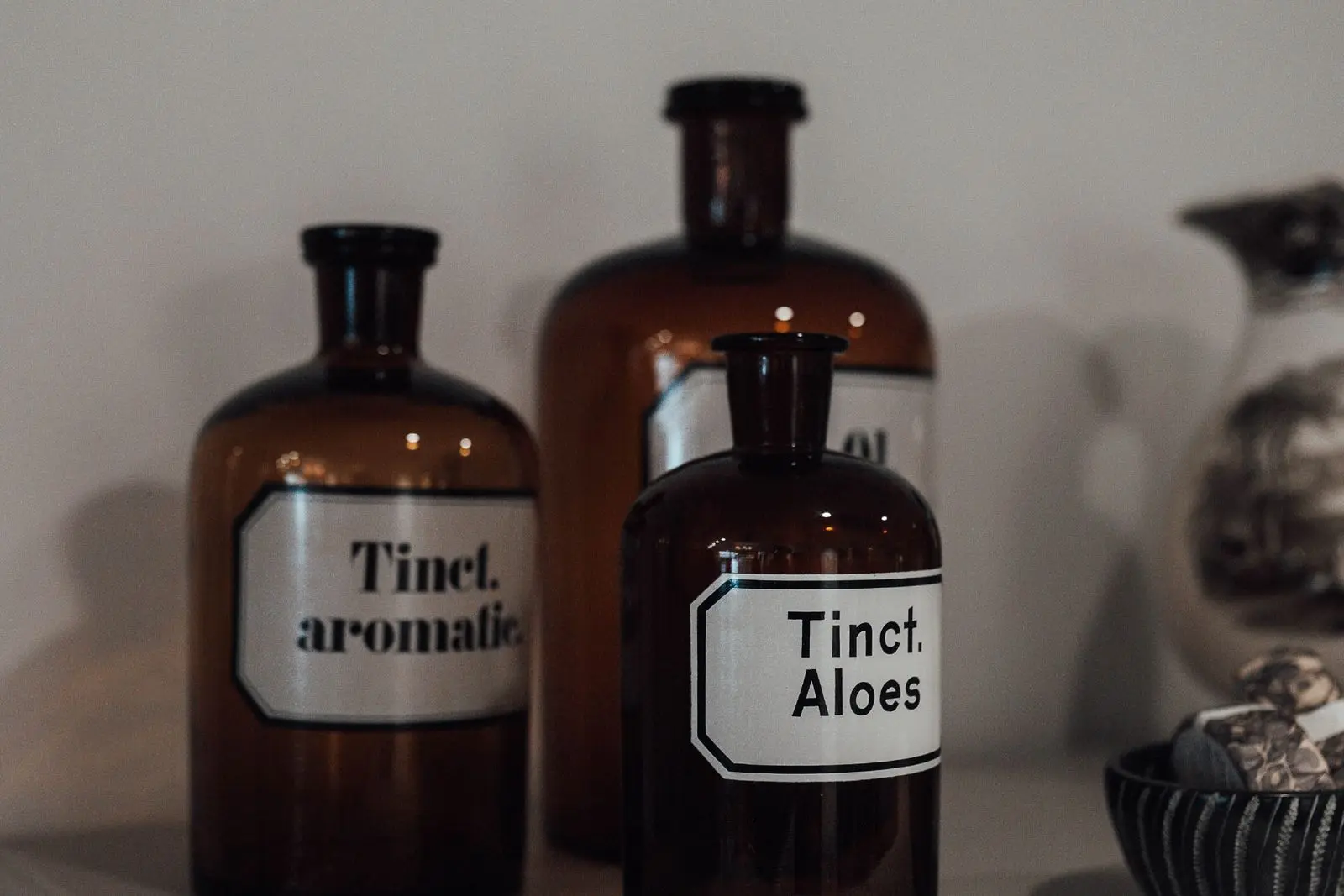 Three labelled apothecary tincture bottles on a shelf in warm, even light.