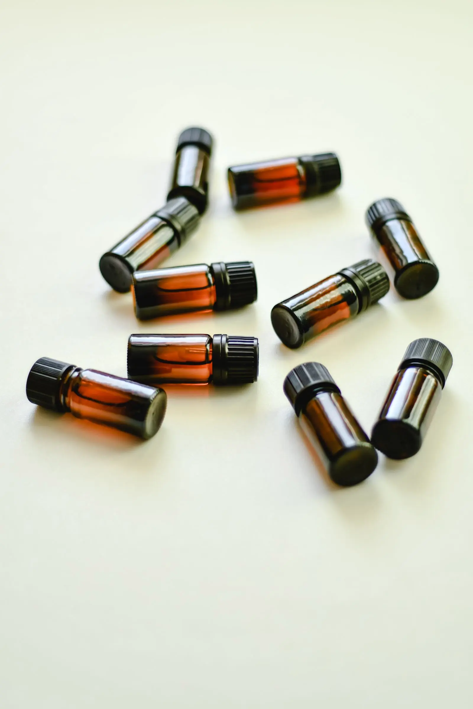 Small amber roller and dropper bottles scattered loosely across a pale surface.
