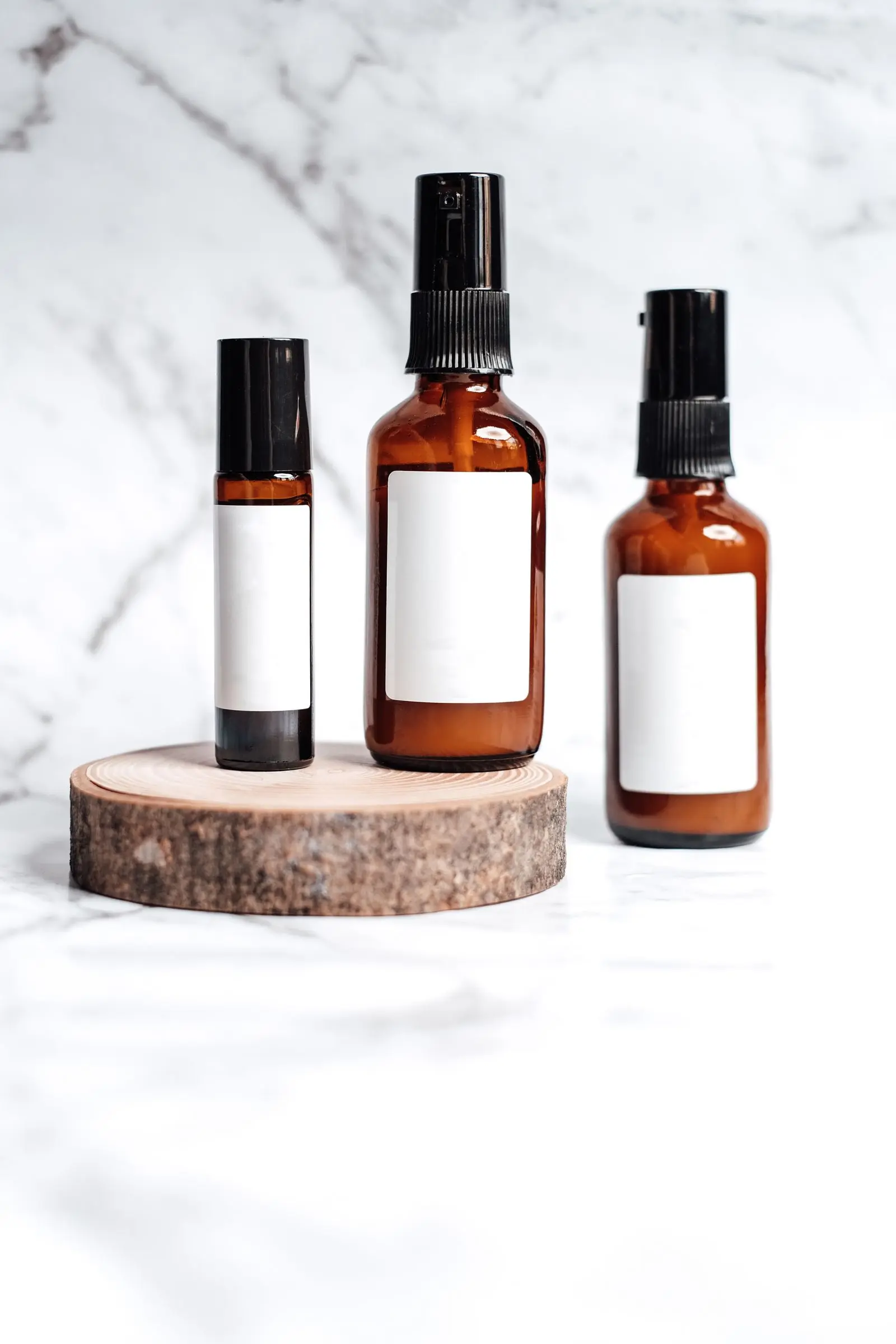 Three amber apothecary bottles of different sizes with blank labels, standing on a wooden disc.