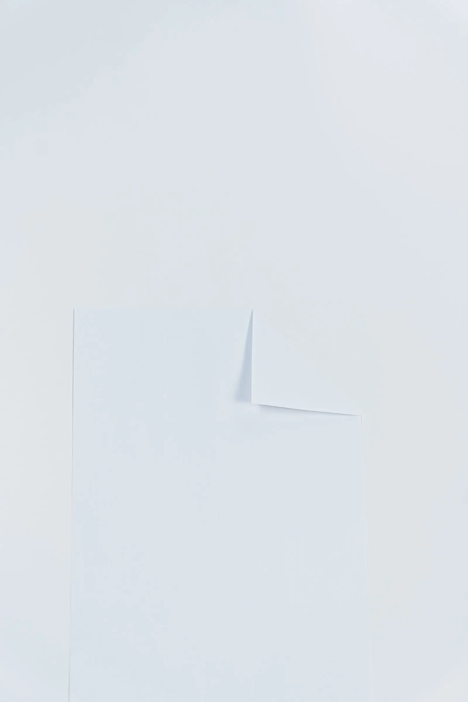 A folded corner of white paper catching a soft diagonal shadow.