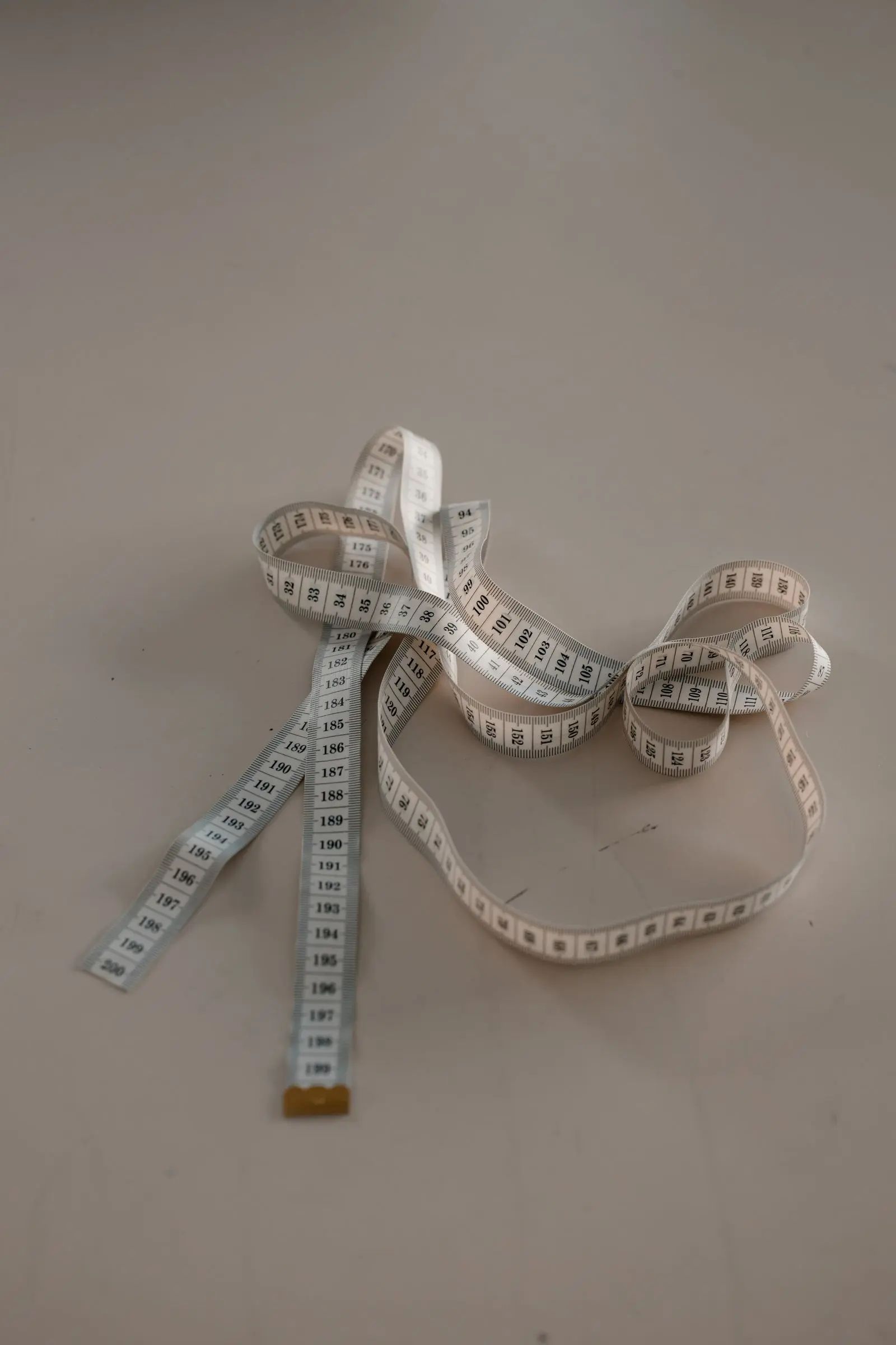 A tape measure coiled loosely across a pale surface.