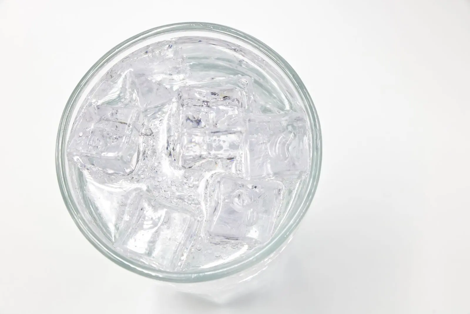 A glass filled with ice cubes and water, viewed directly from above.