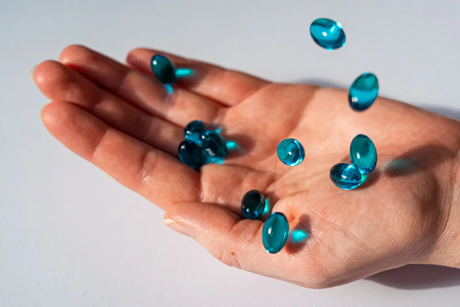 Several translucent blue gel capsules resting in an open palm.