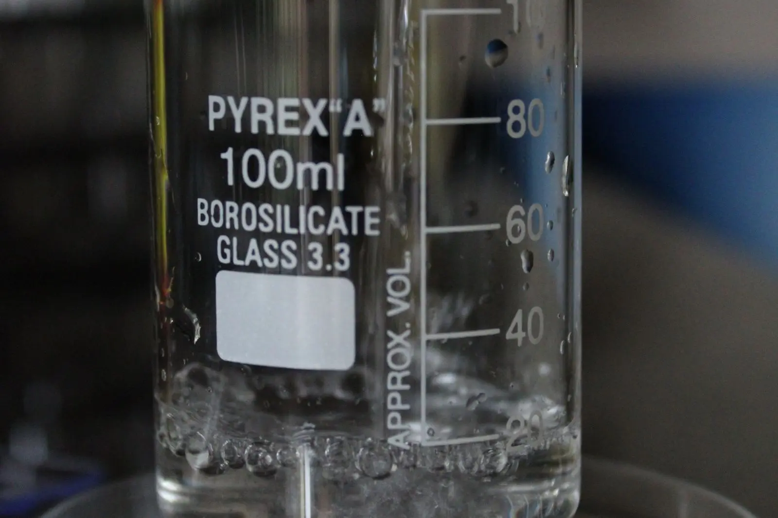Clear water being poured gently down the inside wall of a laboratory beaker.