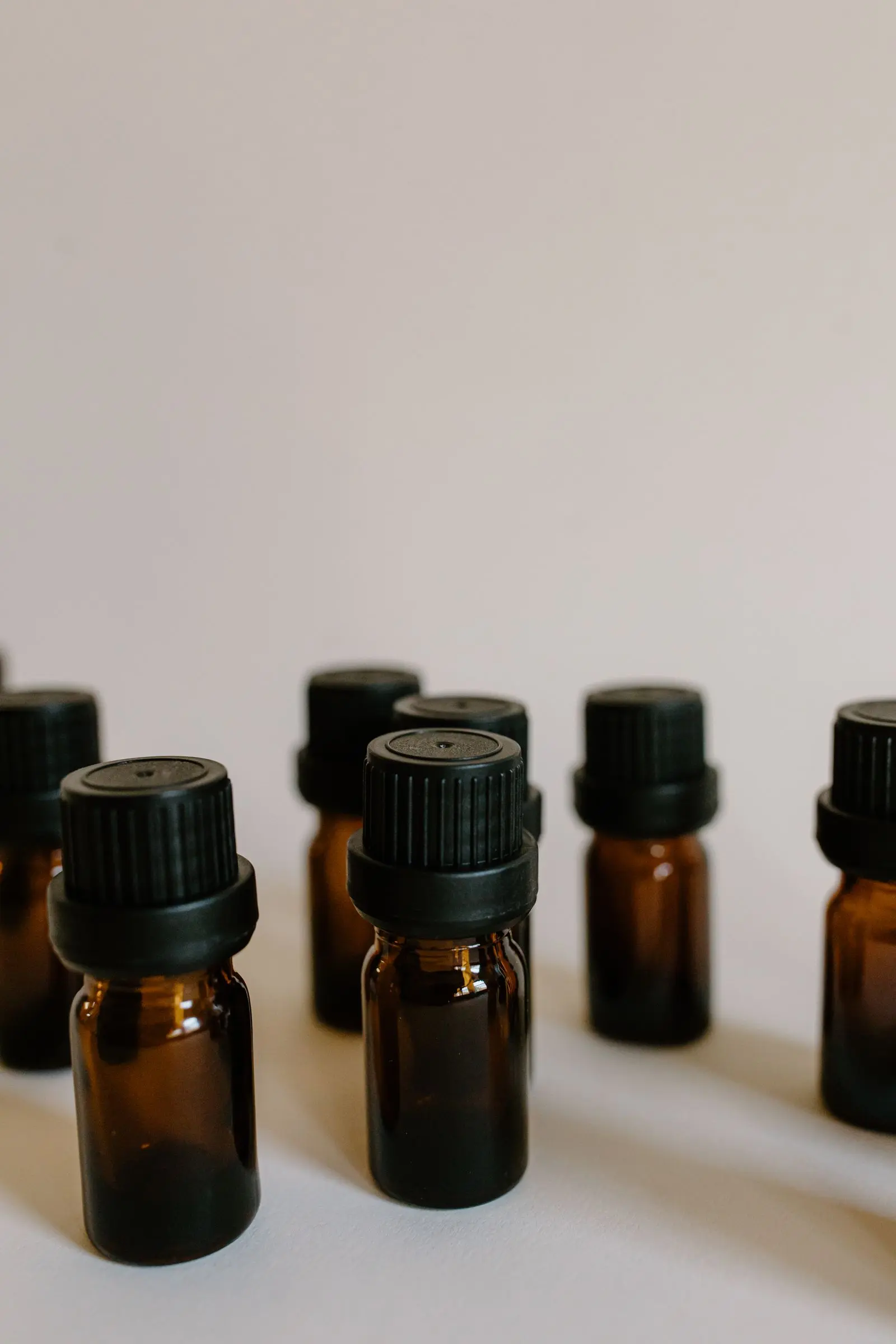 A row of small amber glass bottles with black caps, softly lit from the side.